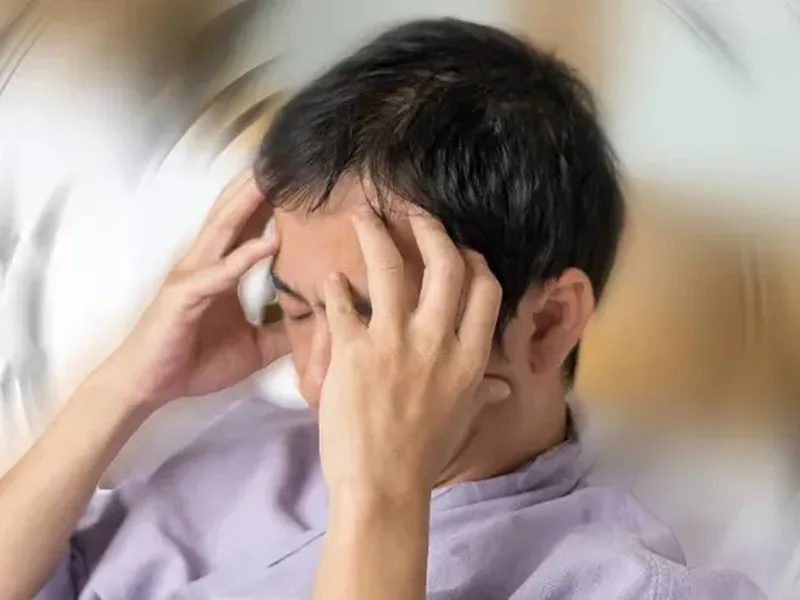 Person holding their head, disoriented by dizziness